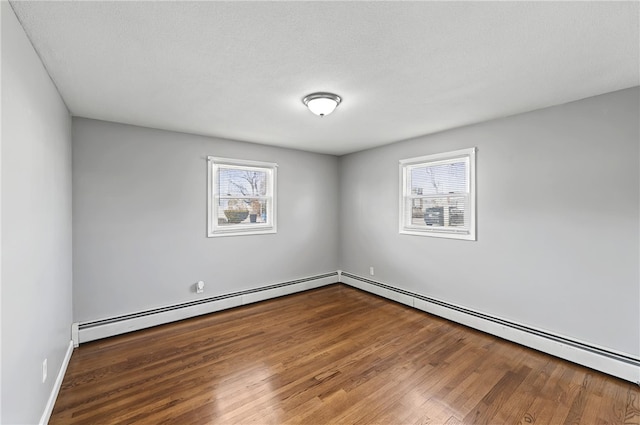 spare room with a baseboard radiator, baseboards, and wood finished floors