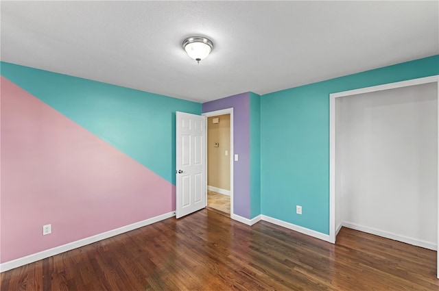 unfurnished bedroom featuring a closet, baseboards, and wood finished floors