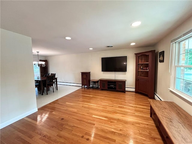 unfurnished living room with a baseboard radiator, light wood-style floors, baseboard heating, and a chandelier