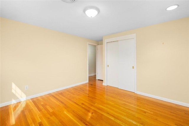 unfurnished bedroom featuring a closet, baseboards, and light wood finished floors