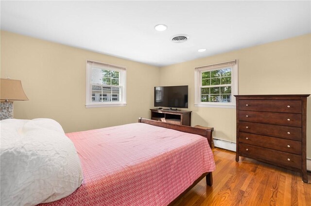 bedroom with recessed lighting, wood finished floors, visible vents, and baseboard heating