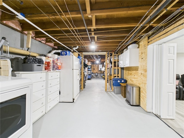 unfinished basement with washer / clothes dryer and freestanding refrigerator