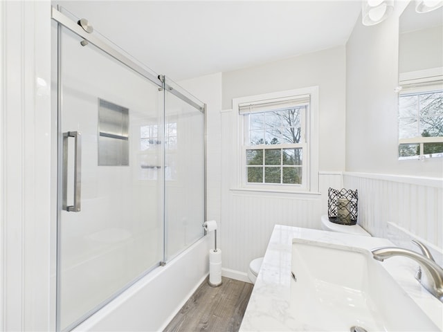 full bath featuring toilet, a wainscoted wall, a wealth of natural light, and a sink