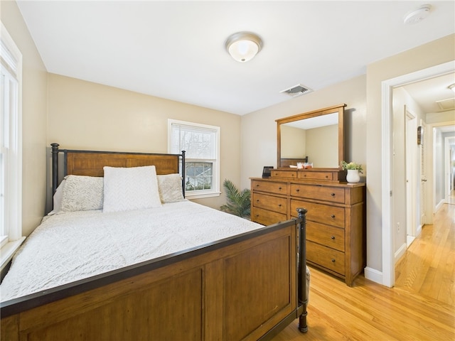 bedroom featuring visible vents, light wood-style flooring, and baseboards