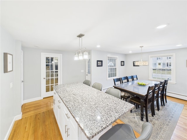 kitchen featuring baseboards, light stone counters, white cabinetry, and light wood-style floors