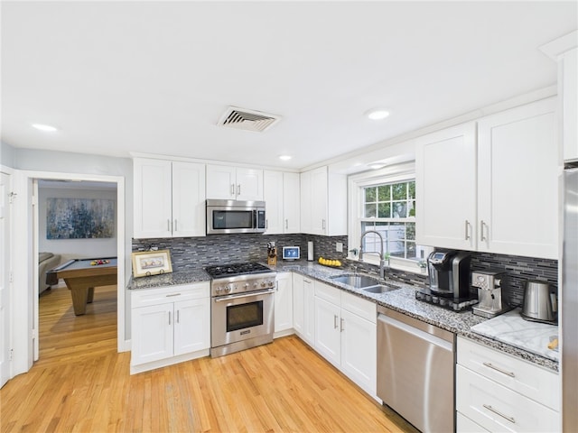 kitchen with light wood-type flooring, visible vents, a sink, white cabinetry, and stainless steel appliances