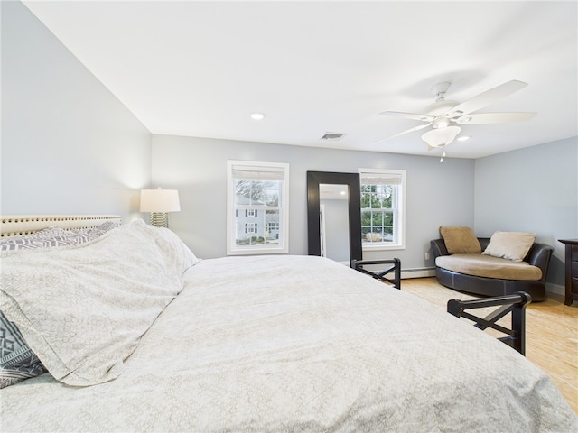 bedroom featuring a ceiling fan, wood finished floors, visible vents, and baseboards