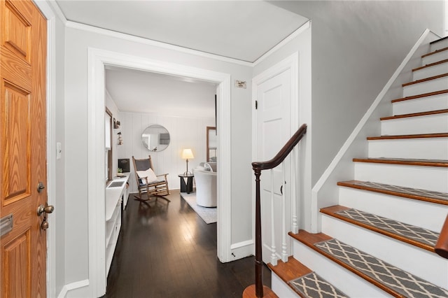 foyer with dark wood finished floors, crown molding, stairs, and baseboards