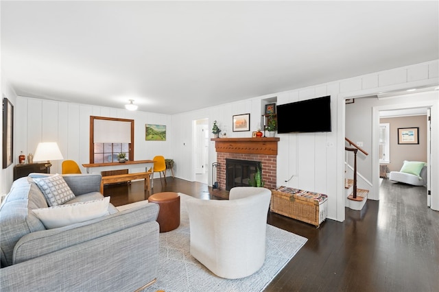 living room with stairs, dark wood-type flooring, and a fireplace