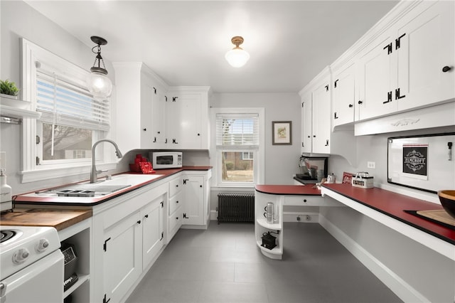 kitchen featuring white appliances, radiator, a sink, white cabinets, and decorative light fixtures