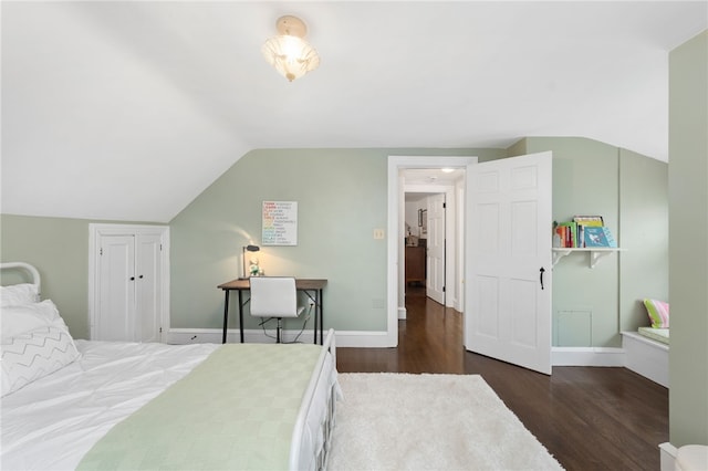 bedroom with vaulted ceiling, wood finished floors, and baseboards