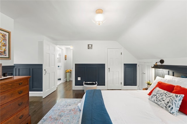 bedroom featuring dark wood finished floors, lofted ceiling, and a wainscoted wall