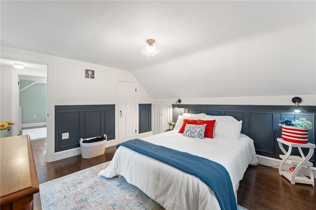 bedroom featuring a decorative wall, wood finished floors, and vaulted ceiling