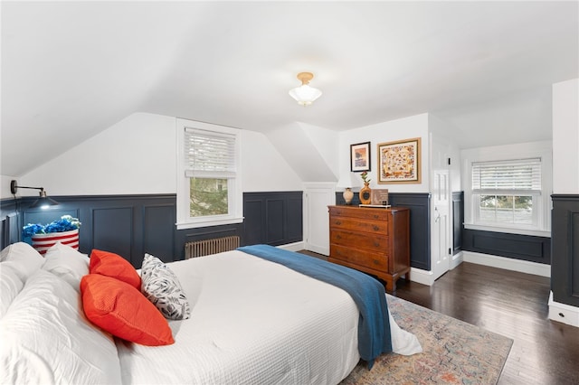 bedroom with vaulted ceiling, wainscoting, radiator, and wood finished floors