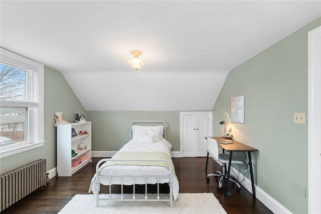 bedroom featuring lofted ceiling, radiator, wood finished floors, and baseboards