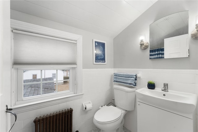 bathroom with radiator, toilet, vanity, wainscoting, and tile walls