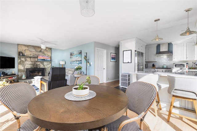 dining area with a toaster, a fireplace, and ceiling fan