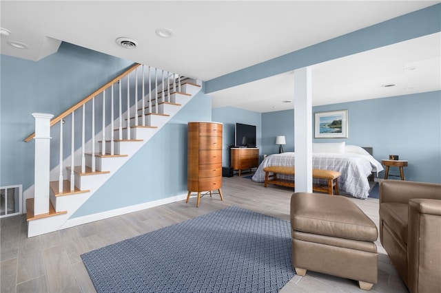 bedroom with wood finished floors, visible vents, and baseboards