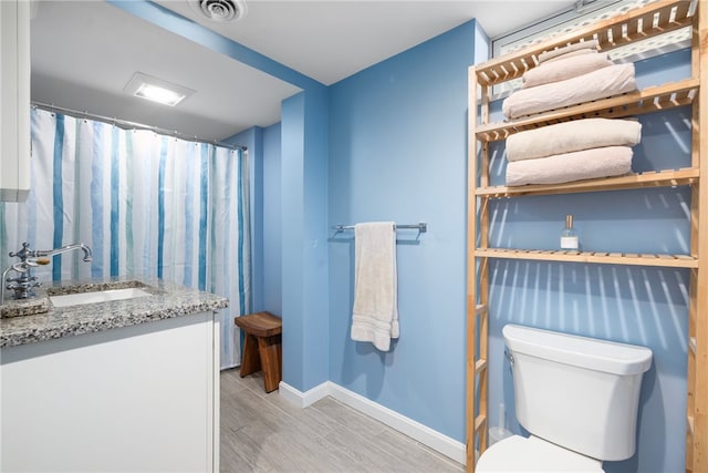 bathroom with visible vents, toilet, wood finished floors, baseboards, and vanity