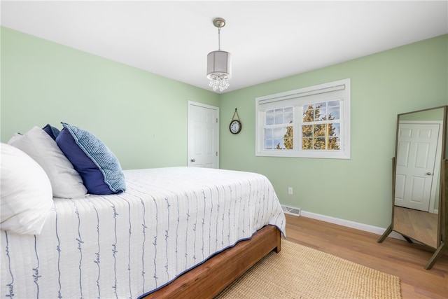 bedroom featuring wood finished floors, baseboards, and visible vents