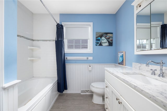 bathroom with visible vents, toilet, shower / bath combo, wainscoting, and vanity