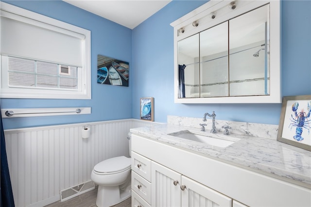 bathroom featuring visible vents, toilet, wainscoting, wood finished floors, and vanity