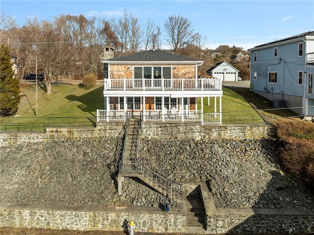 rear view of property featuring an outbuilding, fence, a yard, a balcony, and stairs