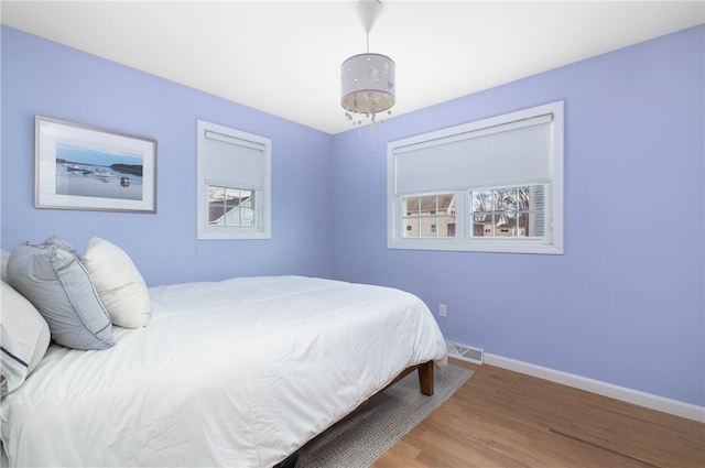 bedroom featuring visible vents, baseboards, and wood finished floors