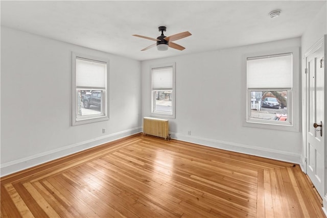 unfurnished room with baseboards, radiator heating unit, light wood-style floors, and a ceiling fan