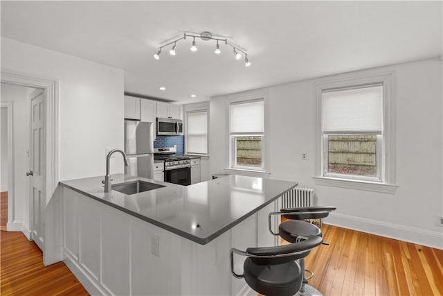 kitchen featuring a breakfast bar area, a peninsula, a sink, white cabinets, and appliances with stainless steel finishes