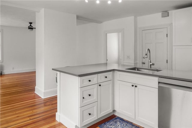 kitchen featuring a sink, light wood-style floors, stainless steel dishwasher, and white cabinetry