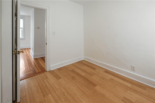 empty room featuring baseboards and light wood finished floors