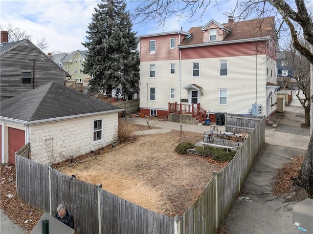 rear view of house featuring a fenced backyard and a chimney