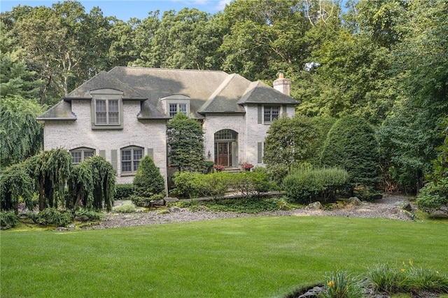 french country inspired facade featuring a front lawn and a chimney