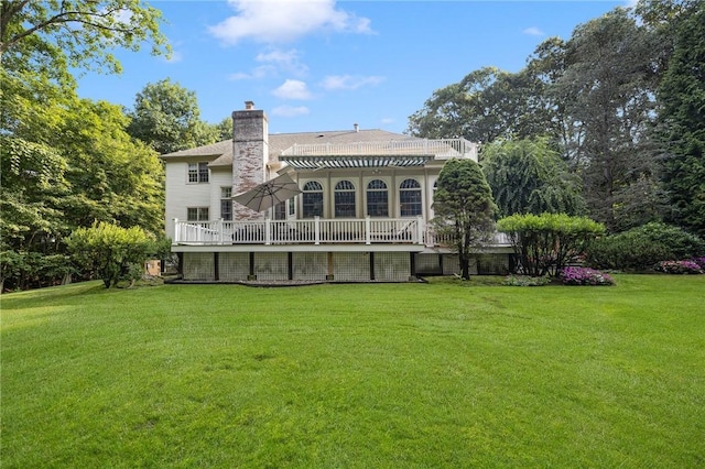 rear view of house featuring a wooden deck, a lawn, and a chimney