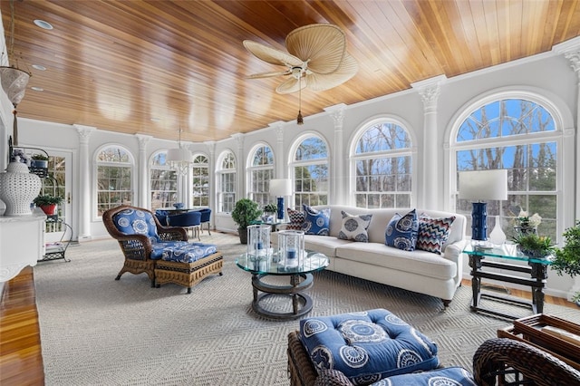 sunroom with plenty of natural light, wooden ceiling, a ceiling fan, and ornate columns