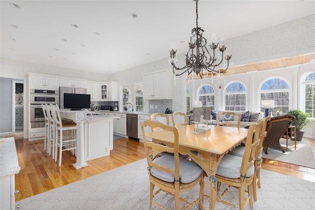 dining room with a notable chandelier, light wood-style floors, and wallpapered walls