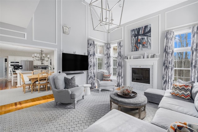 living room with wood finished floors, a high ceiling, a fireplace, and a chandelier