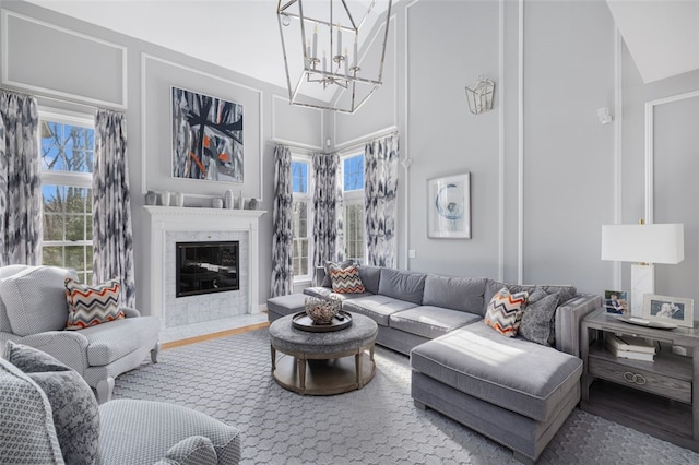 living area with a notable chandelier, a fireplace, a high ceiling, and wood finished floors