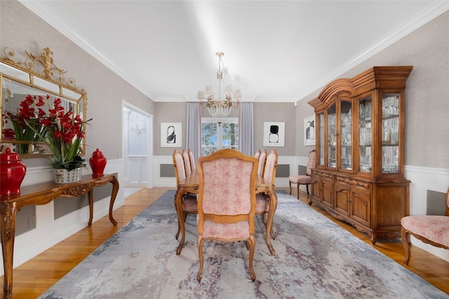 dining area featuring a chandelier, wainscoting, crown molding, and wood finished floors