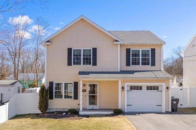 traditional home with aphalt driveway, roof with shingles, a garage, and fence