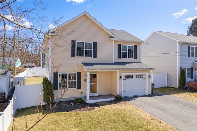 traditional home with aphalt driveway, a garage, a front yard, and fence