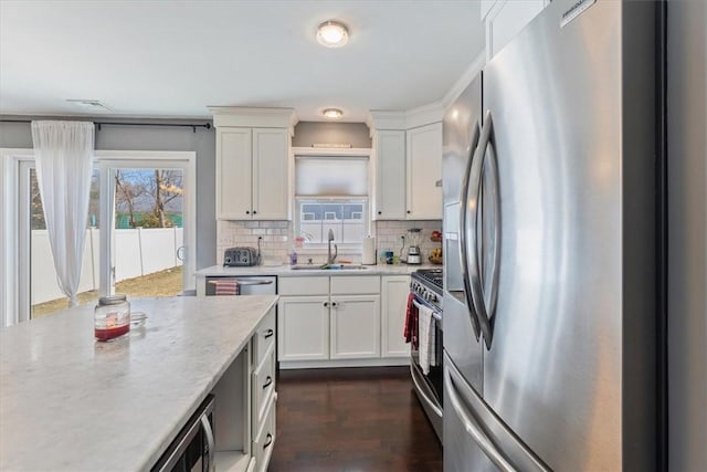 kitchen featuring backsplash, dark wood finished floors, appliances with stainless steel finishes, white cabinetry, and a sink