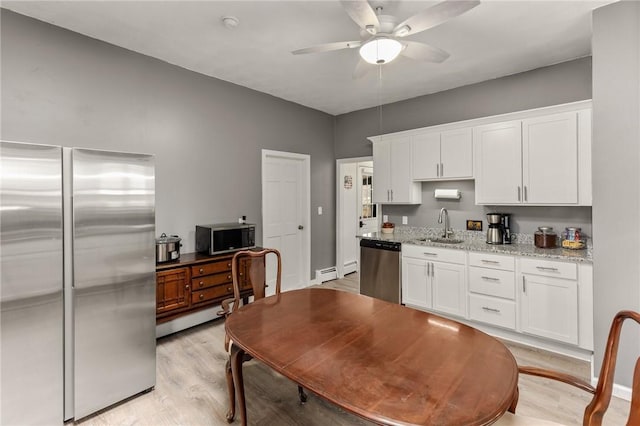 kitchen with ceiling fan, a sink, white cabinets, appliances with stainless steel finishes, and light wood-type flooring