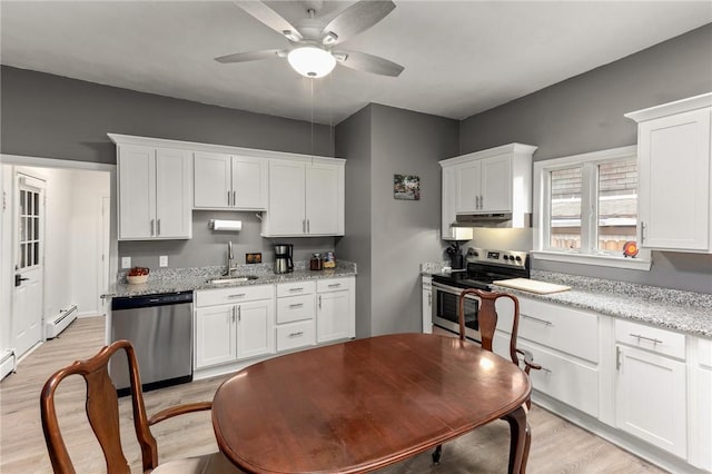 kitchen with a baseboard radiator, a sink, stainless steel appliances, under cabinet range hood, and white cabinetry