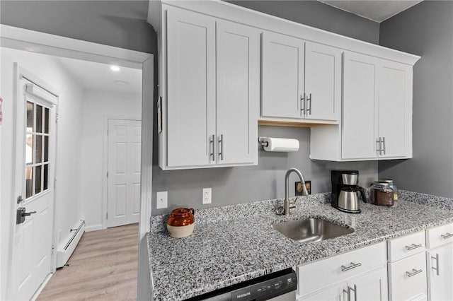 kitchen featuring a baseboard heating unit, light stone counters, light wood-style floors, white cabinets, and a sink