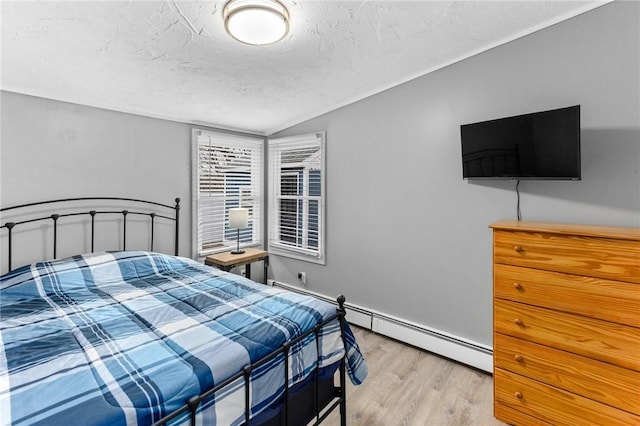 bedroom with a baseboard heating unit, vaulted ceiling, light wood finished floors, and a textured ceiling