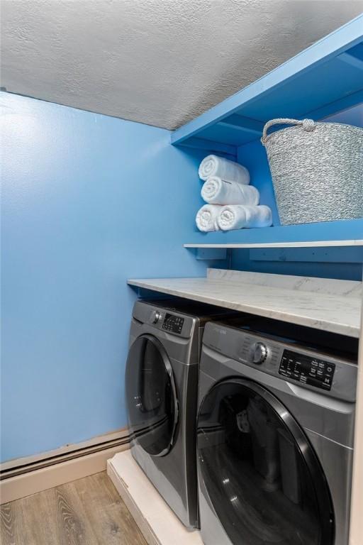 laundry area with a textured ceiling, wood finished floors, laundry area, and washer and clothes dryer