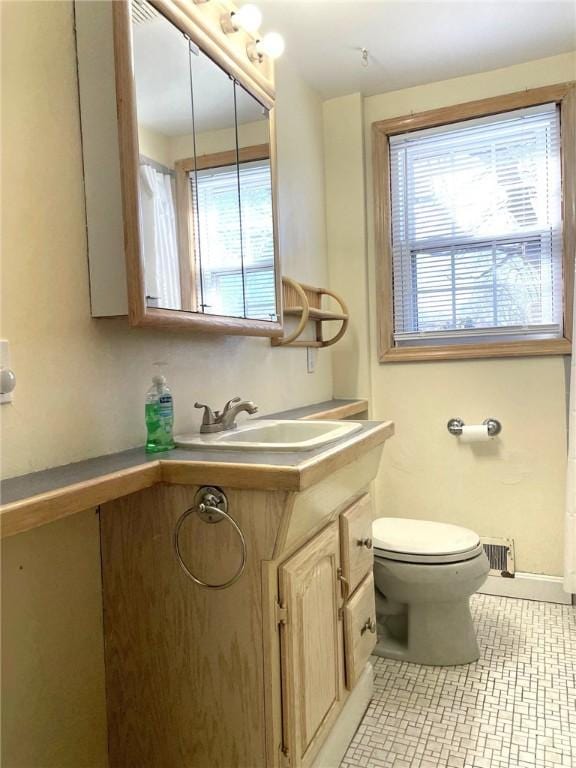 bathroom with visible vents, toilet, a healthy amount of sunlight, and vanity