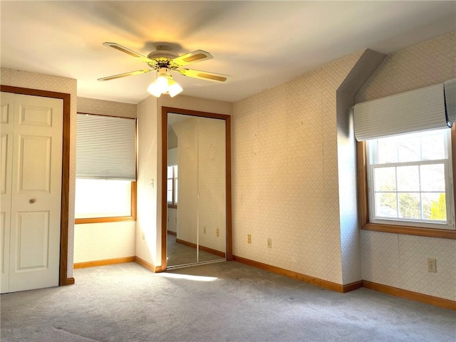 unfurnished bedroom featuring baseboards, carpet floors, two closets, and wallpapered walls